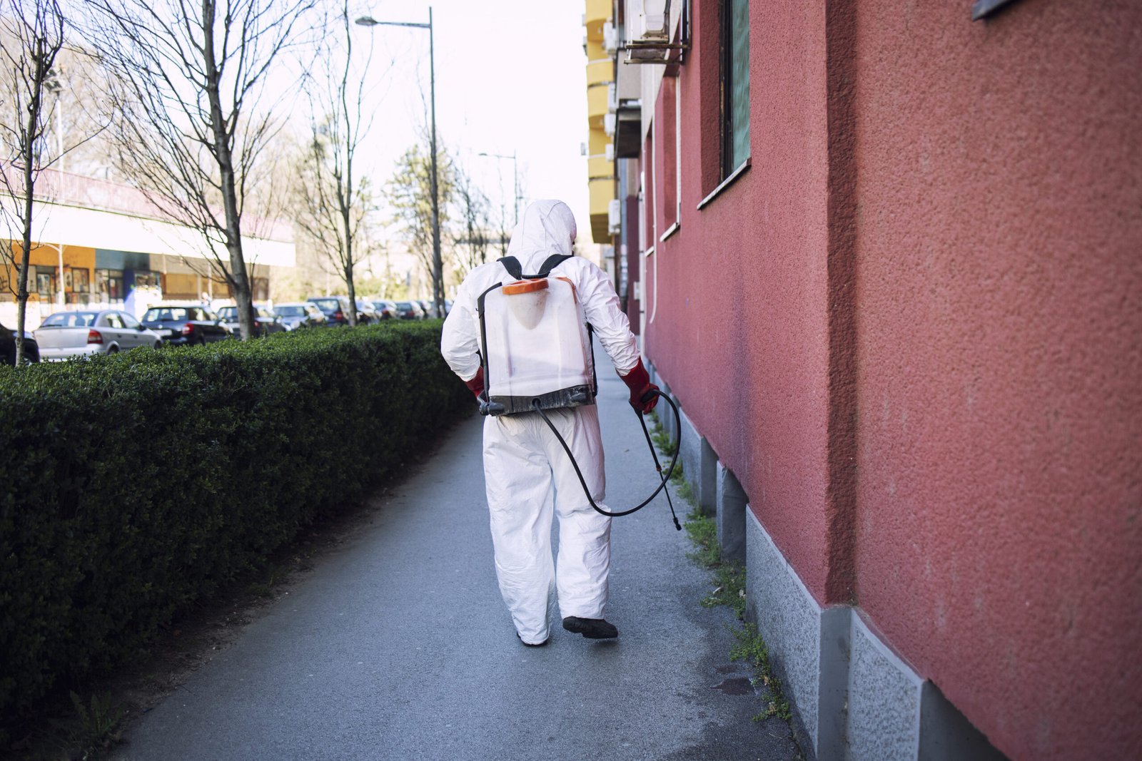 Worker chemical protection suit spraying disinfectant public surfaces scaled